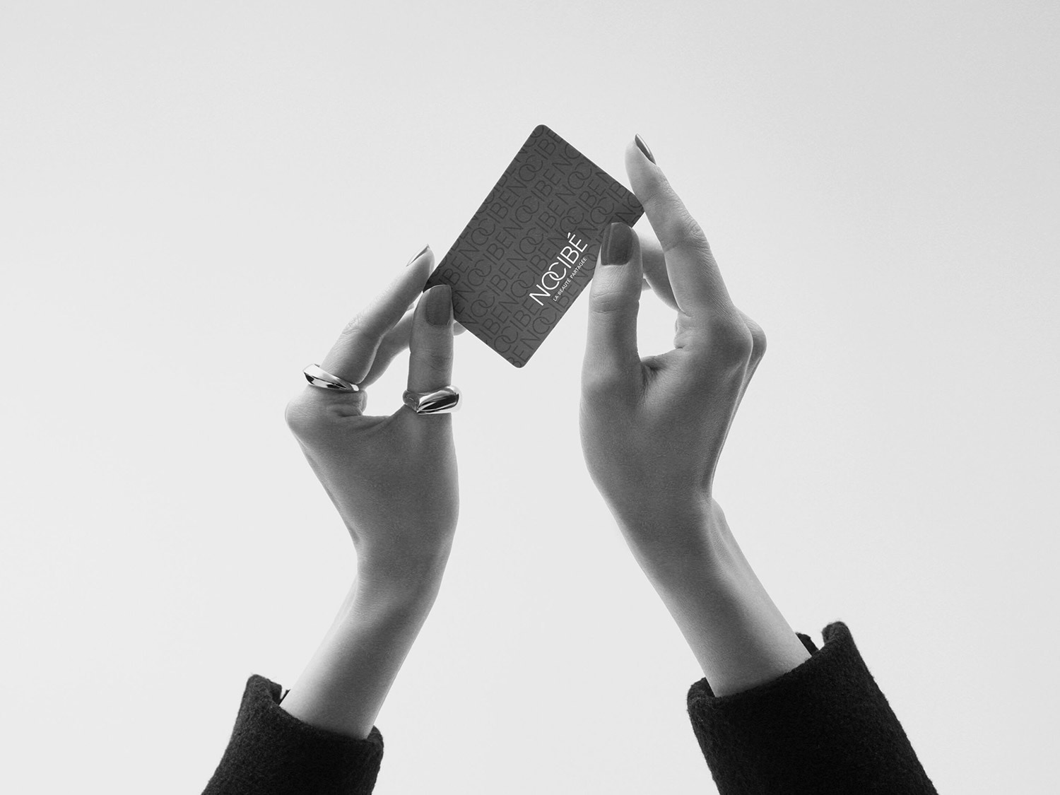 Deux mains tenant une carte Nocibé, mettant en valeur l'élégance et le style associés à la marque.