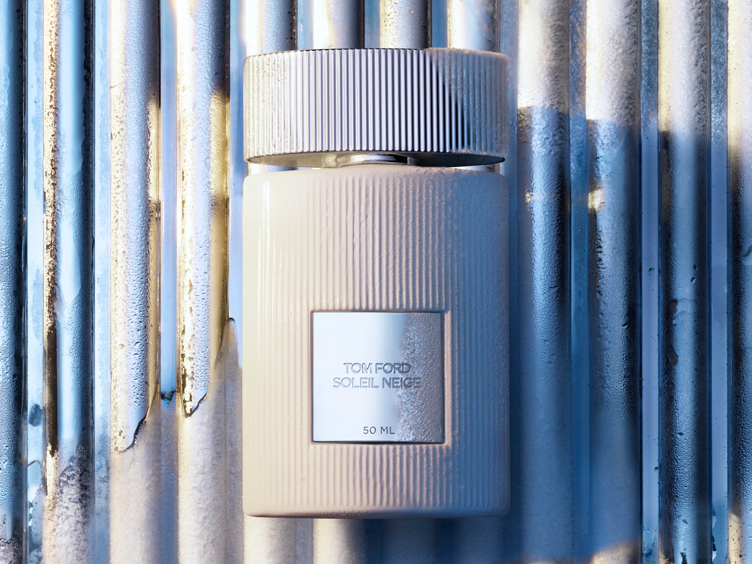 Tom Ford Soleil Neige 50 ml buteliukas kreminės spalvos fone su sidabriniais dryžiais su metaliniu dangteliu.