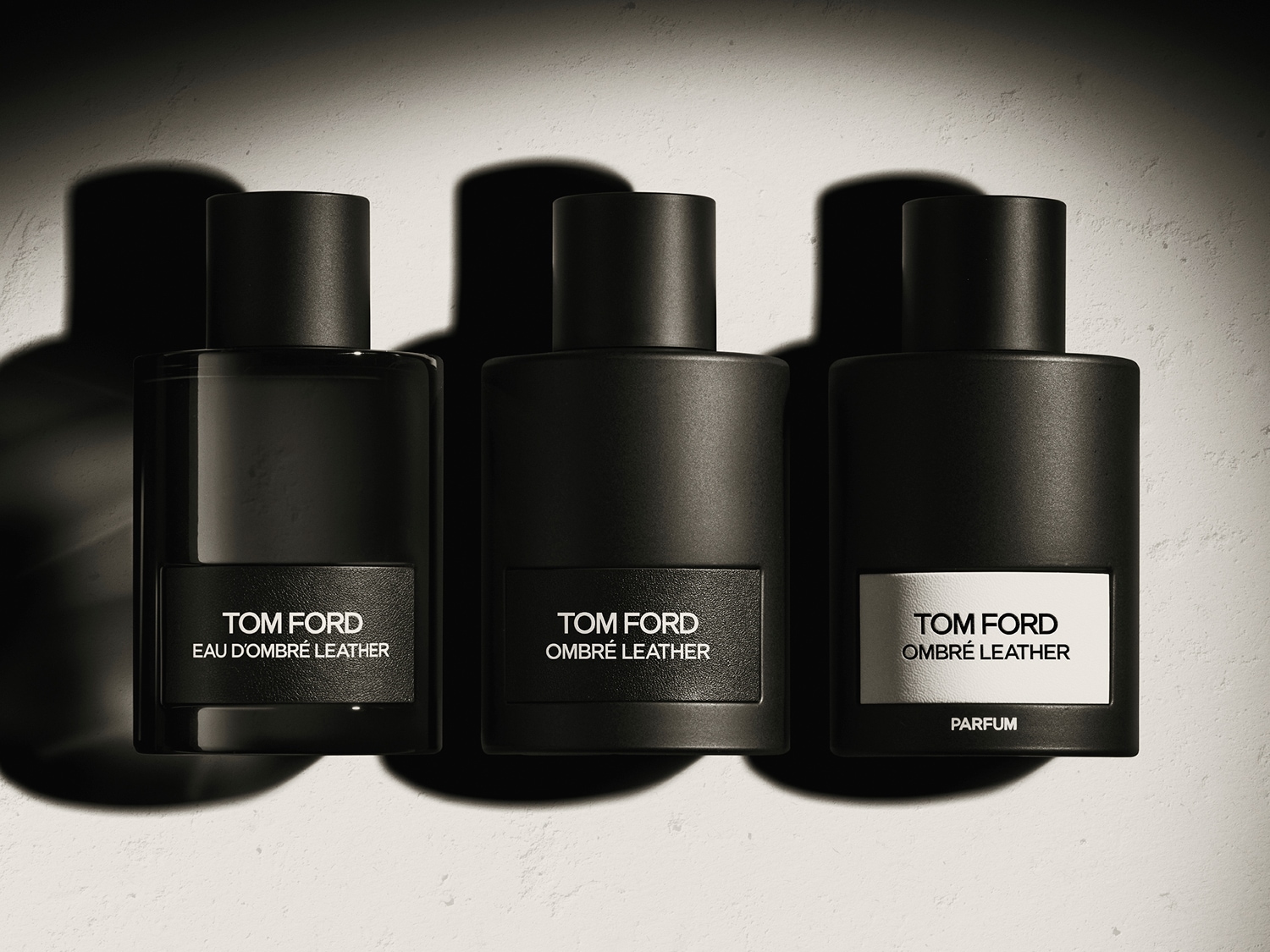 Drei Tom Ford Ombré Leather Düfte in schwarzen Flakons liegen auf einer hellen Oberfläche
