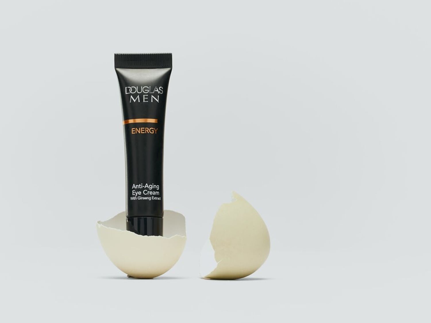 Douglas Men Energy Anti-Aging Augencreme mit Ginseng-Extrakt in einer schwarzen Tube, die in einer zerbrochenen Eierschale steht.