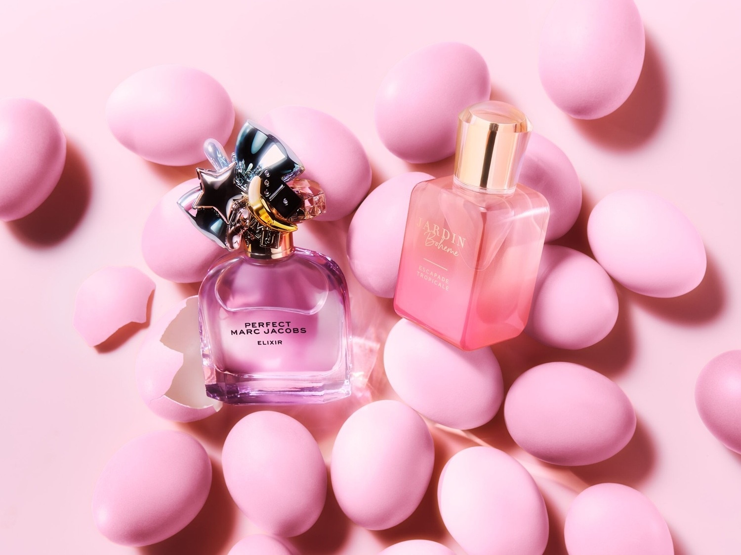 Rosa Eier umgeben Perfect Marc Jacobs Elixir und Jardin Boheme Parfum, die in durchsichtigen Flaschen mit goldenen Akzenten präsentiert werden.