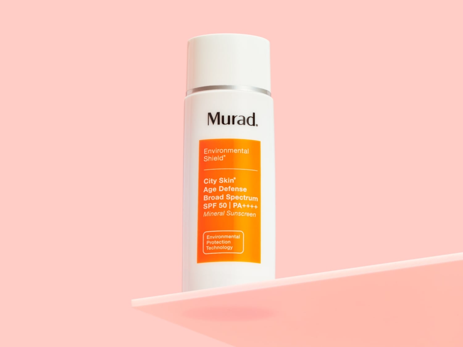 Biała butelka Murad Environmental Shield City Skin Age Defense Broad Spectrum SPF 50 na różowym tle, zapewniająca ochronę przed słońcem i zanieczyszczeniami.