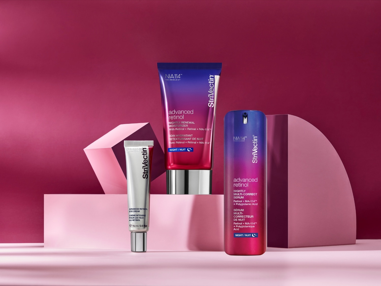 Trzy produkty StriVectin Advanced Retinol na tle w odcieniach różu: krem pod oczy w srebrnej tubce, krem nawilżający w tubce w kolorze granatowo-różowym oraz serum w butelce w kolorze granatowo-różowym.