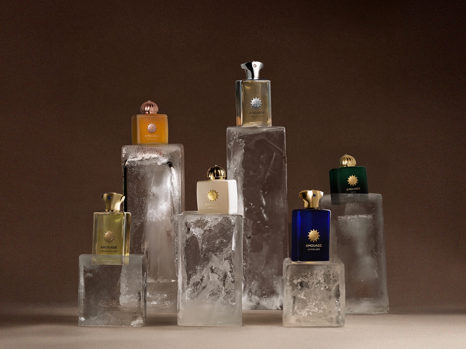 Eine Sammlung von Amouage-Parfümflaschen in verschiedenen Farben, die auf Eisblöcken präsentiert werden, darunter Gelb, Weiß, Blau und Grün, vor einem braunen Hintergrund.