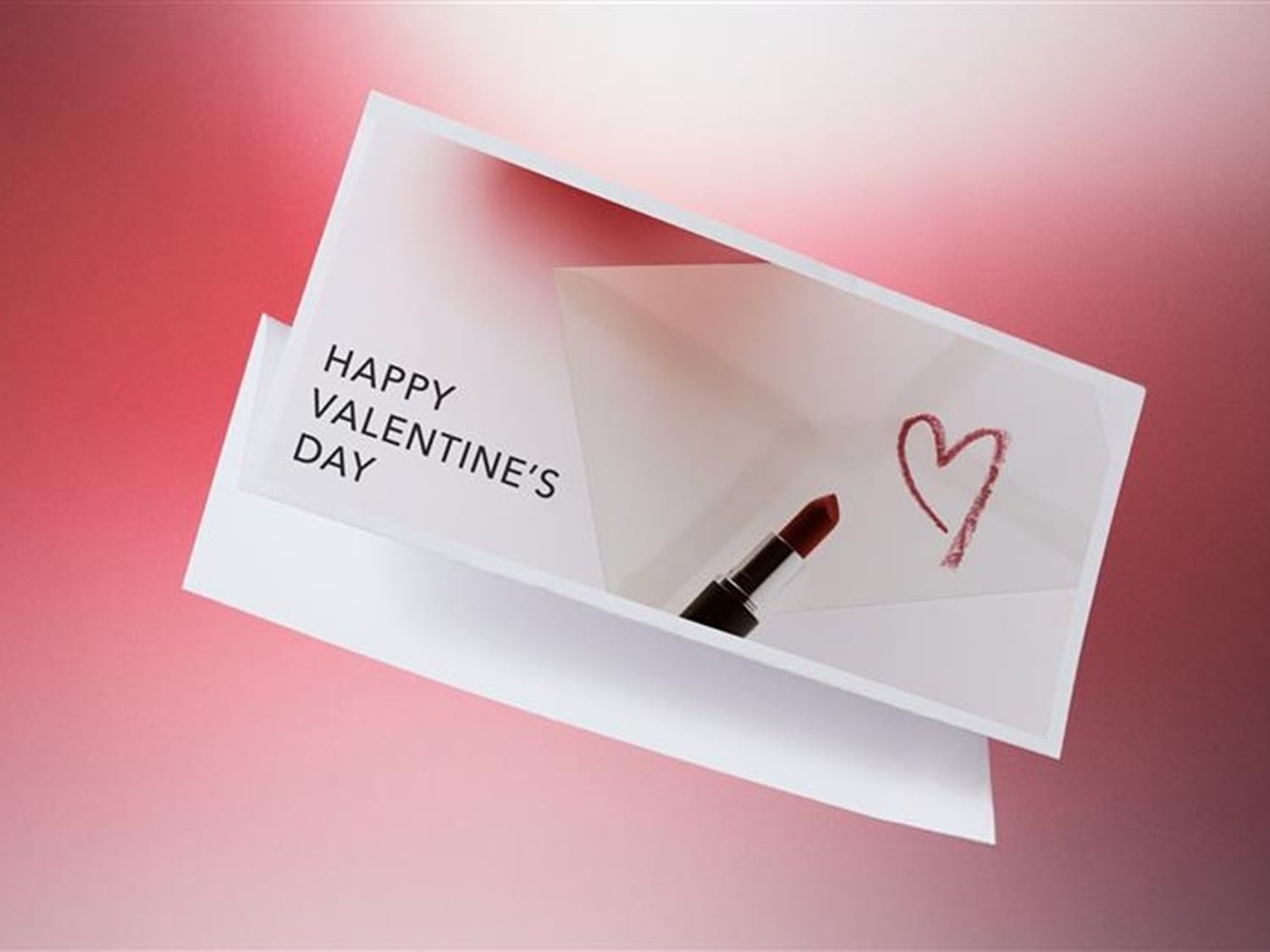 Walentynkowa kartka z napisem „Happy Valentine's Day”, obok której leży szminka w sztyfcie i narysowane serce.