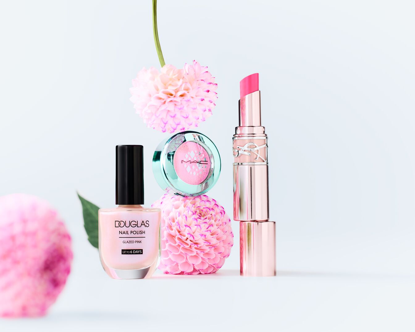 Entdecke eine elegante Auswahl an Make-up-Produkten, darunter ein zartrosa Nagellack von Douglas, ein schimmernder MAC-Lidschatten und ein luxuriöser Lippenstift von Yves Saint Laurent, allesamt in sanften Rosatönen.