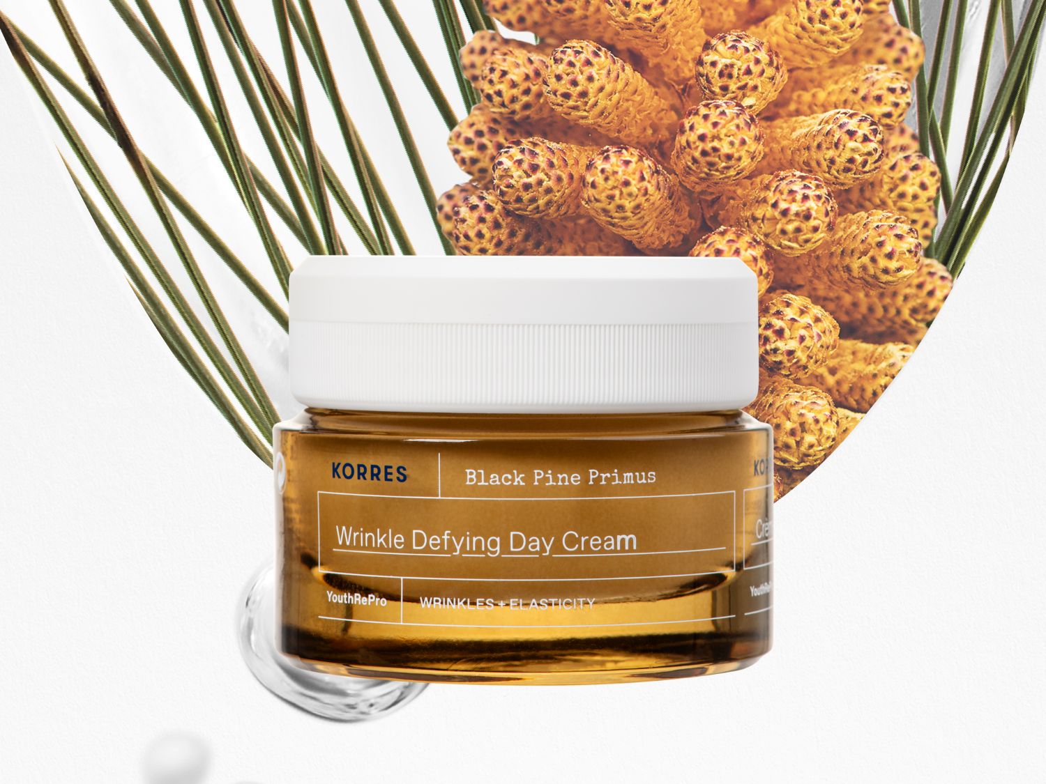 Słoik brązowego kremu na dzień Korres Black Pine Primus Wrinkle Defying Day Cream z białą nakrętką, obok którego znajdują się zielone igły sosny i szyszka.