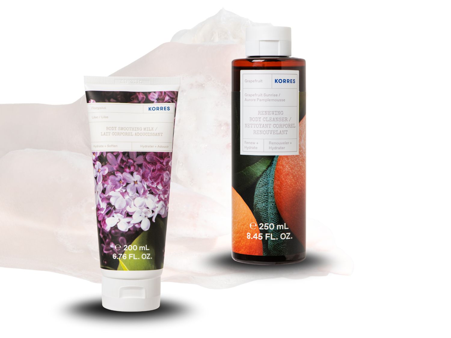 Balsam do ciała Korres o zapachu bzu w białym opakowaniu z fioletowymi kwiatami oraz żel do mycia ciała o zapachu grejpfruta w brązowej butelce.