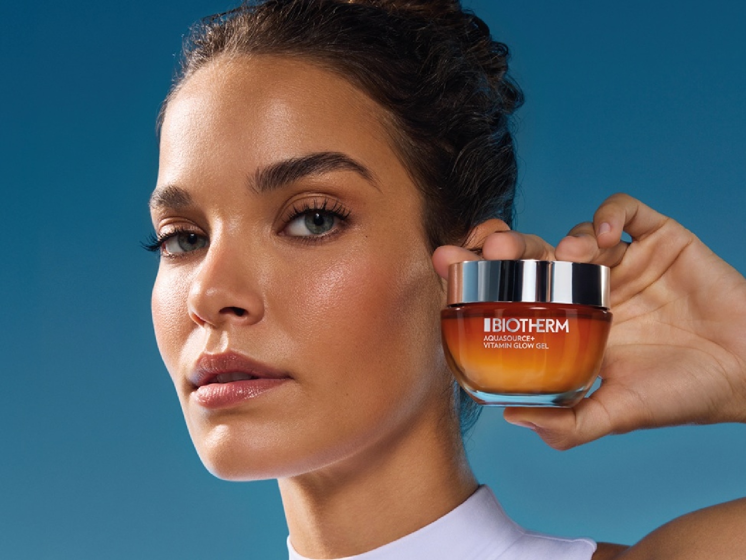 Une femme tient un pot de gel éclat vitamine Aquasource+ de Biotherm, qui promet un teint lumineux et hydraté.