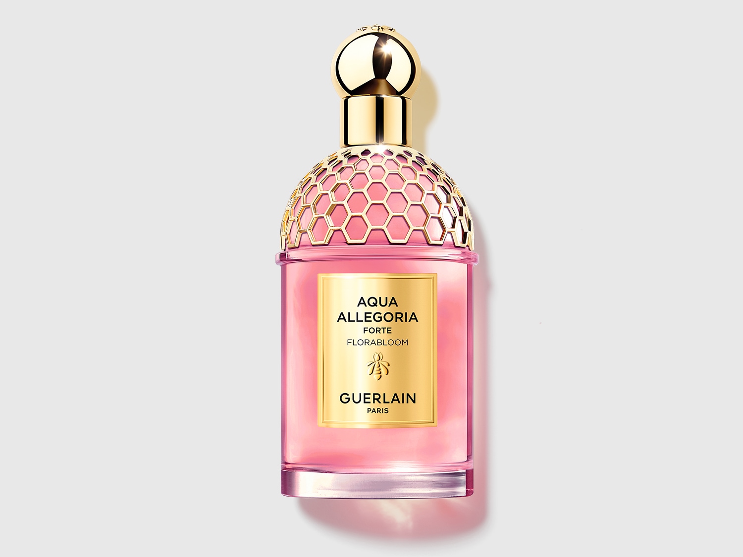 Découvrez Aqua Allegoria Forte Florabloom de Guerlain, un parfum floral rosé présenté dans un flacon élégant avec un bouchon doré en nid d'abeille.
