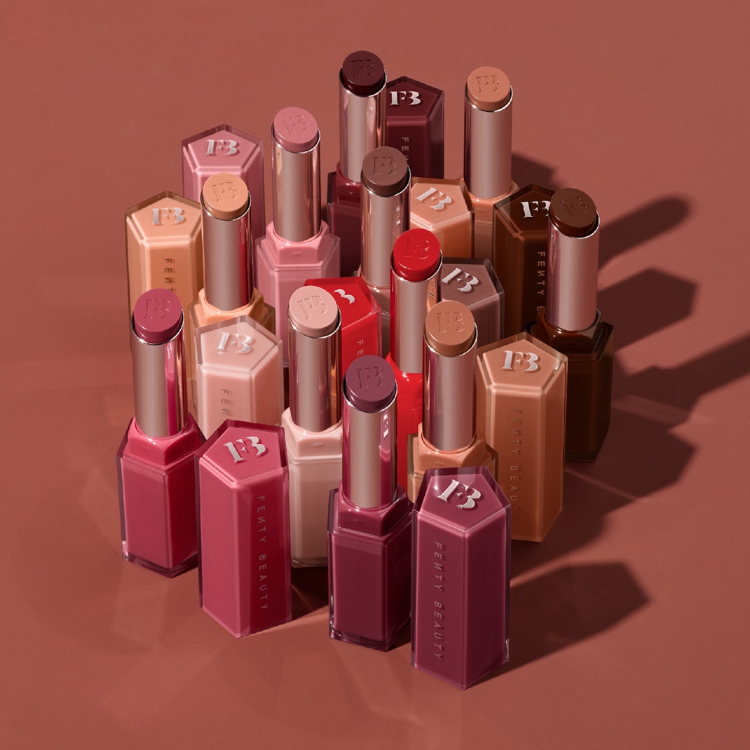 Découvrez une gamme de rouges à lèvres Fenty Beauty aux teintes riches et variées, présentés dans des emballages hexagonaux élégants, offrant une couleur intense et une hydratation longue durée.