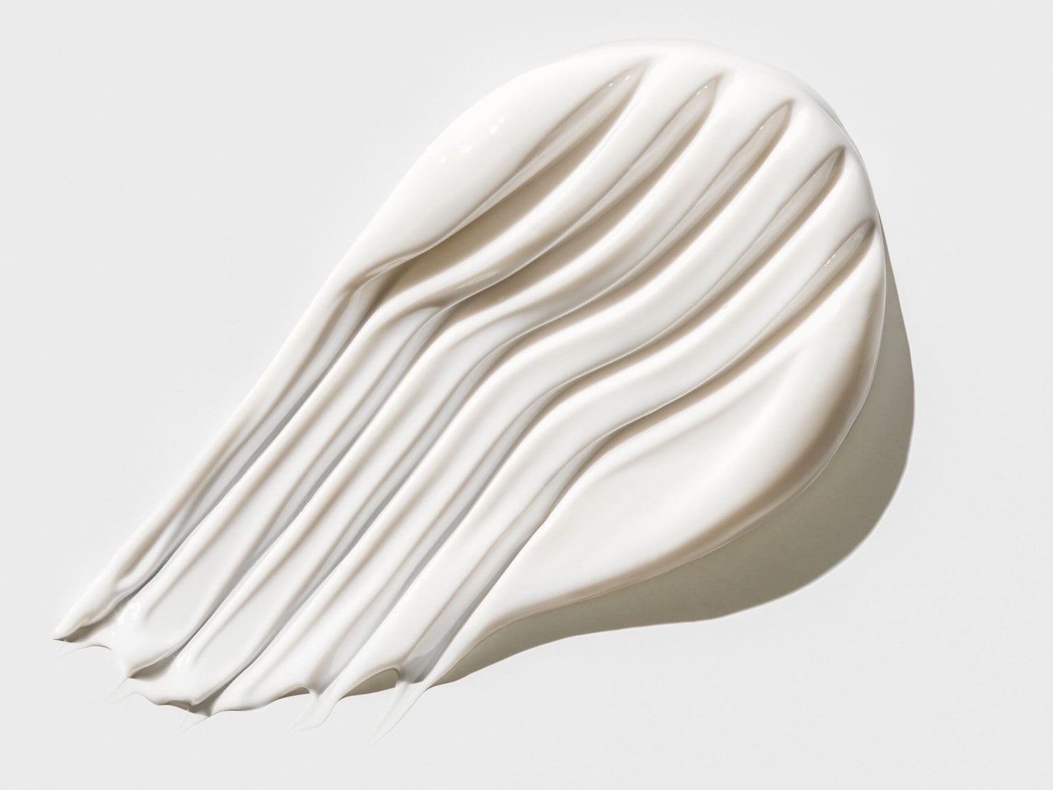 Een close-up van een dikke, witte crème die in golvende lijnen is uitgesmeerd, waardoor de gladde textuur en hydraterende eigenschappen worden benadrukt.