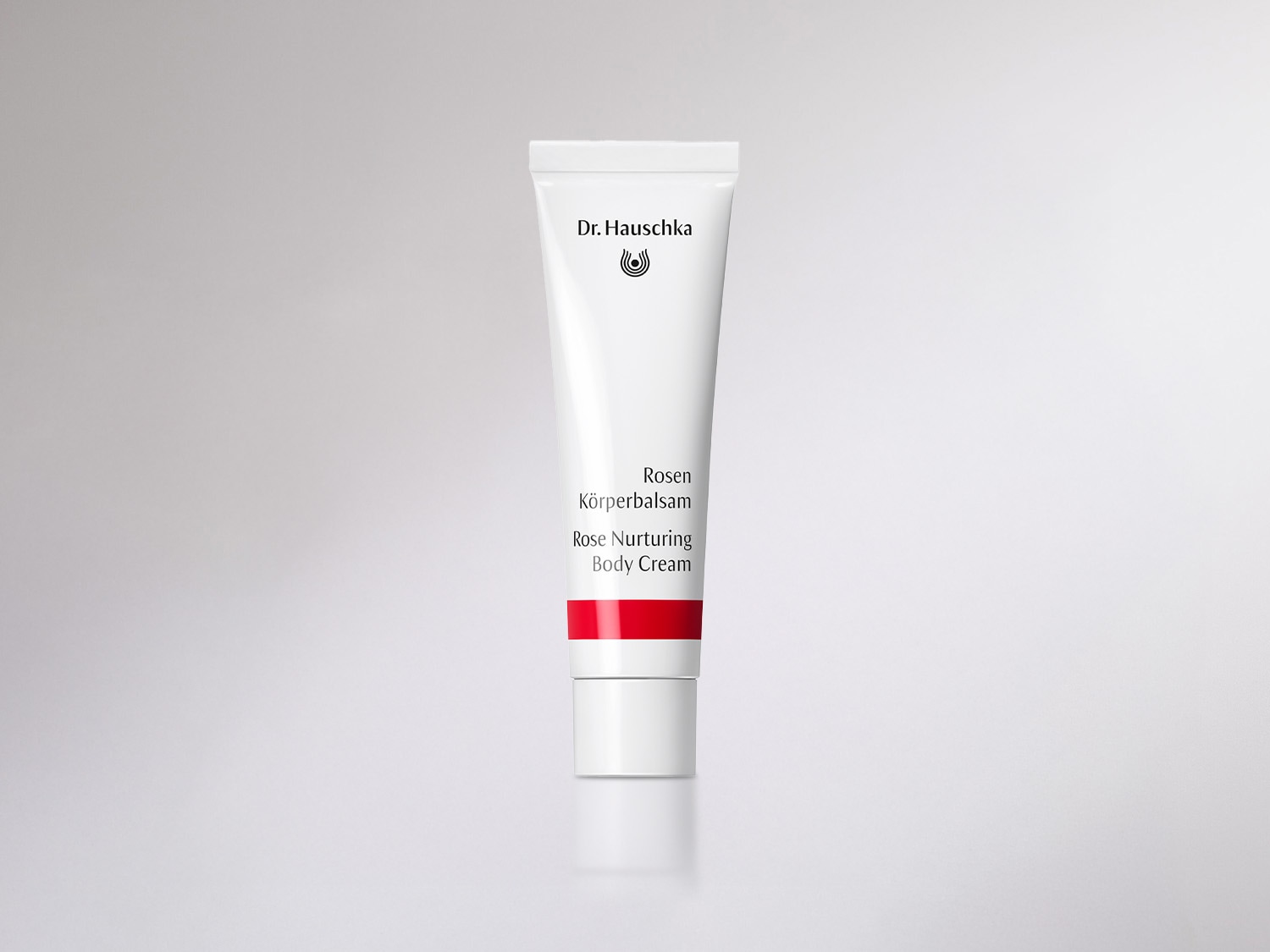 Weiße Tube Dr. Hauschka Rosen Körperbalsam mit rotem Streifen, die eine reichhaltige Pflege für trockene Haut verspricht.