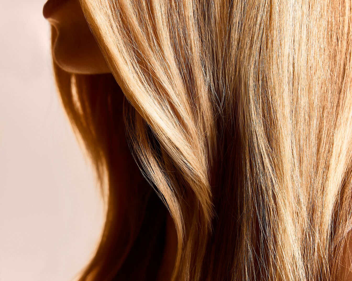 Nahaufnahme von glänzendem, gewelltem, blondem Haar, das weich und gesund aussieht.