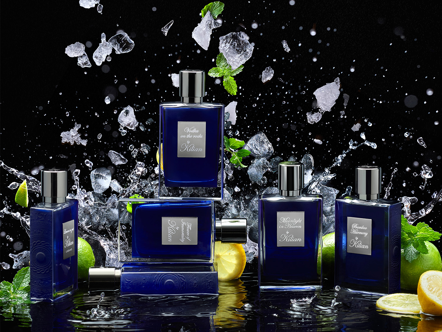 Eine Kollektion von Kilian-Parfums in blauen Flakons, umgeben von Eiswürfeln, Zitrusfrüchten und Minze.