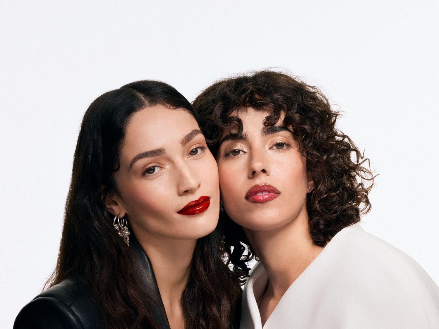 Zwei Frauen mit glänzenden Lippenstiften in Rot- und Rosatönen, die ihre Lippen betonen und einen Hauch von Glamour verleihen.