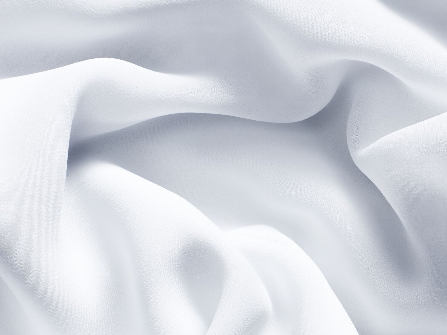 Nahaufnahme von weißem, gewelltem Stoff, der ein Gefühl von Reinheit und Eleganz vermittelt.