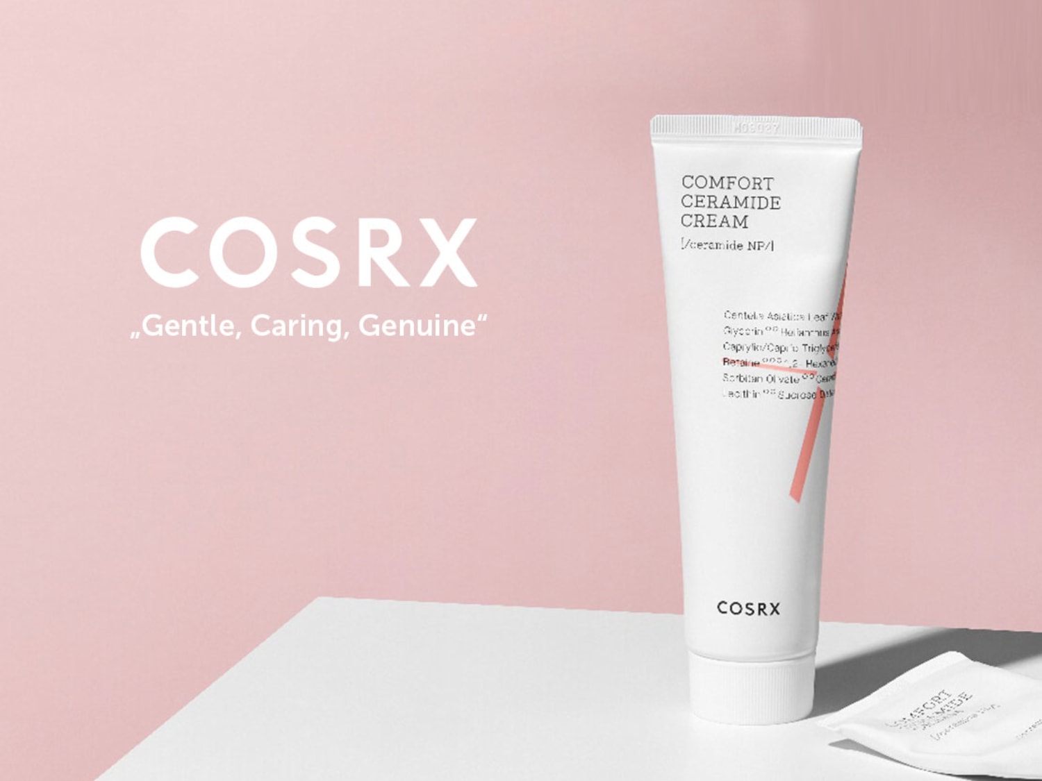 Na różowym tle biała tuba kremu COSRX Comfort Ceramide Cream z napisem „Delikatny, troskliwy, prawdziwy”.