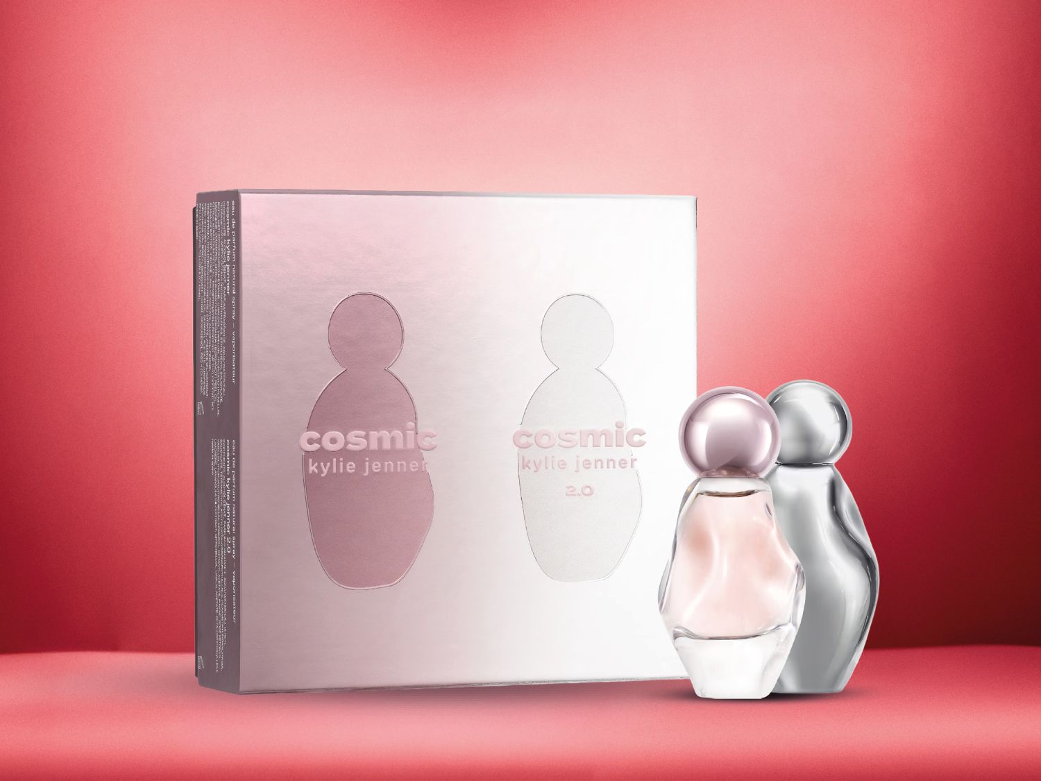 Cosmic Kylie Jenner parfumset met een zilveren doos en twee flessen, een roze en een zilveren, tegen een rode achtergrond.