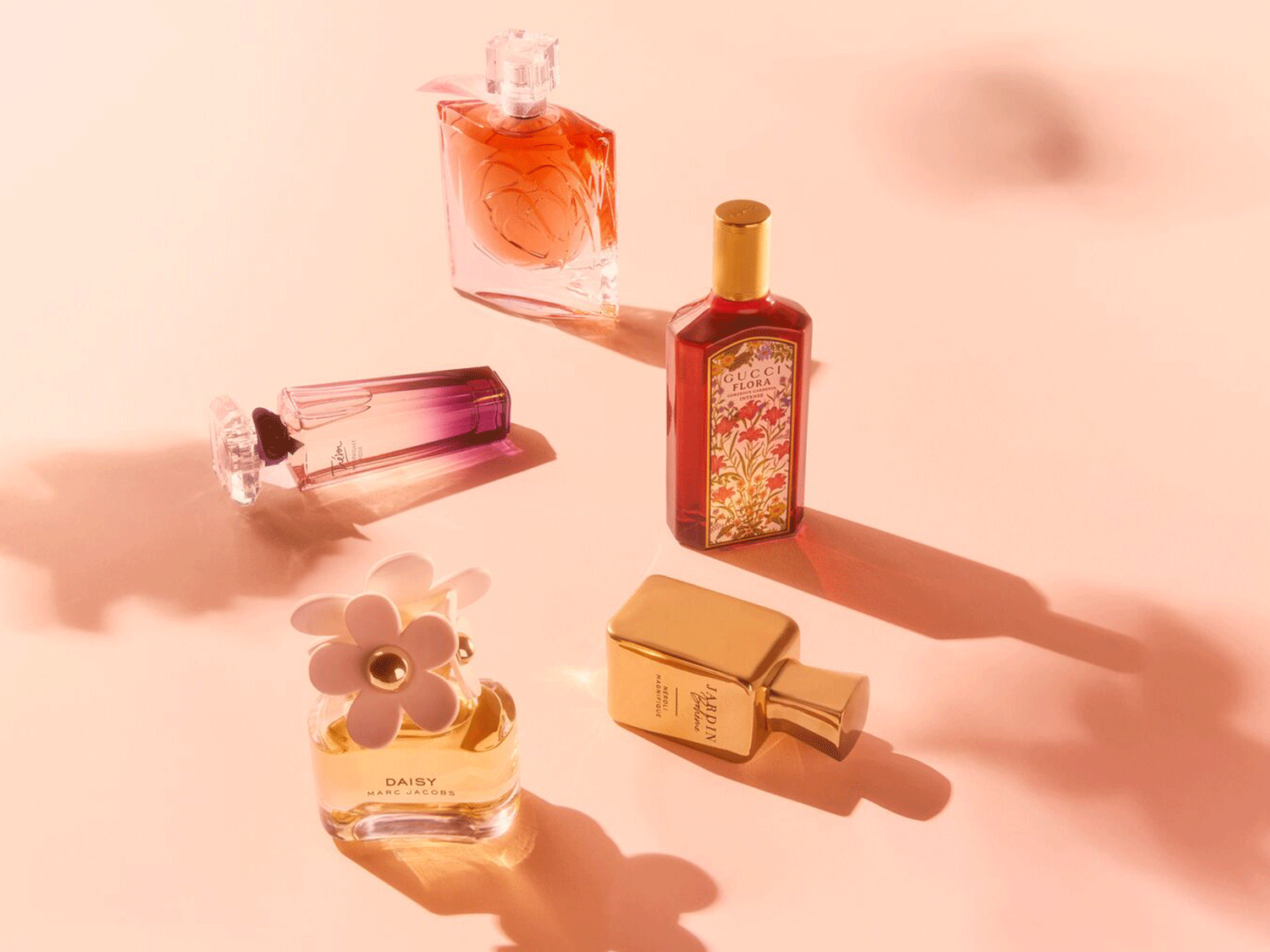 Eine Sammlung von Parfümflaschen verschiedener Marken, darunter Gucci Flora in einer rot gemusterten Flasche und Daisy von Marc Jacobs mit einem Gänseblümchen-Flakon.