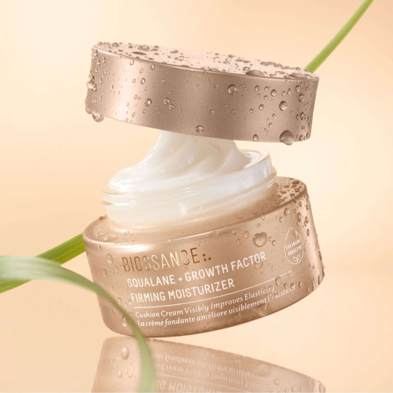 Die Biossance Squalane + Growth Factor Feuchtigkeitspflege präsentiert sich in einer Dose mit geöffnetem Deckel, die eine cremefarbene Creme enthüllt, die die Elastizität sichtbar verbessert.