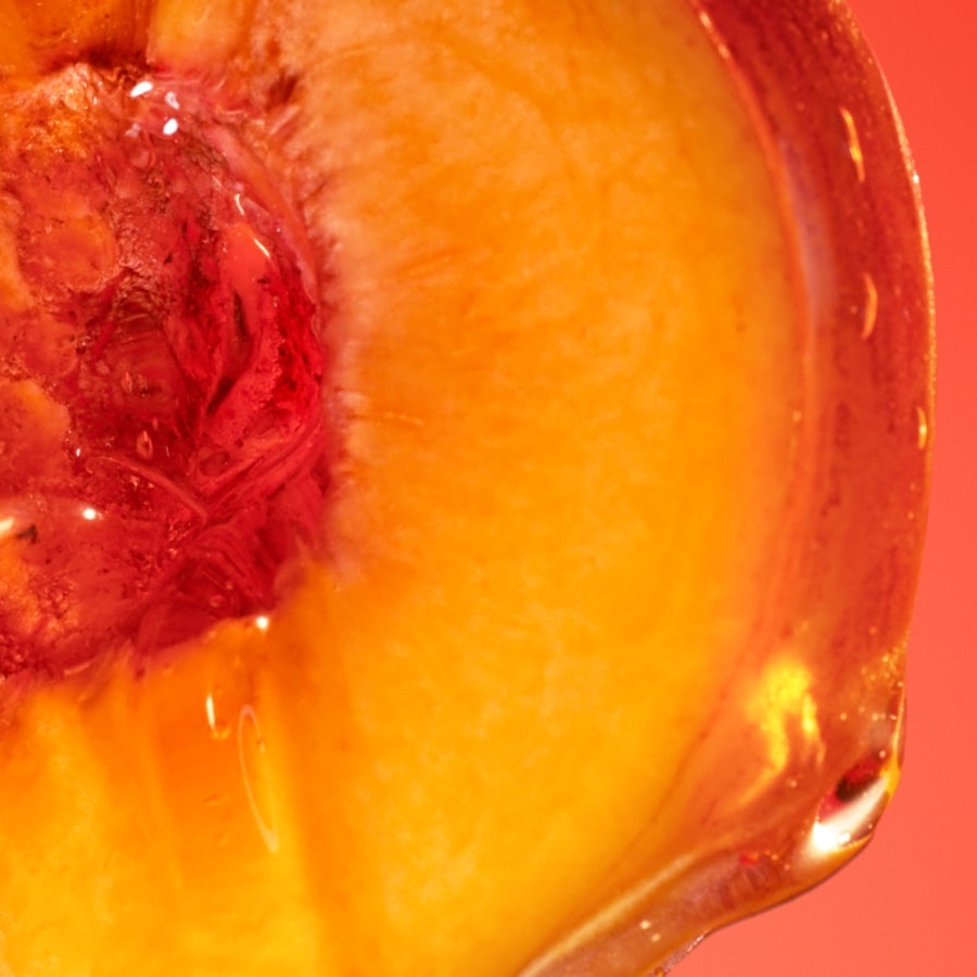 Nahaufnahme eines halben, saftigen Pfirsichs mit rotem Kern und glänzender, orangefarbener Oberfläche vor einem roten Hintergrund.