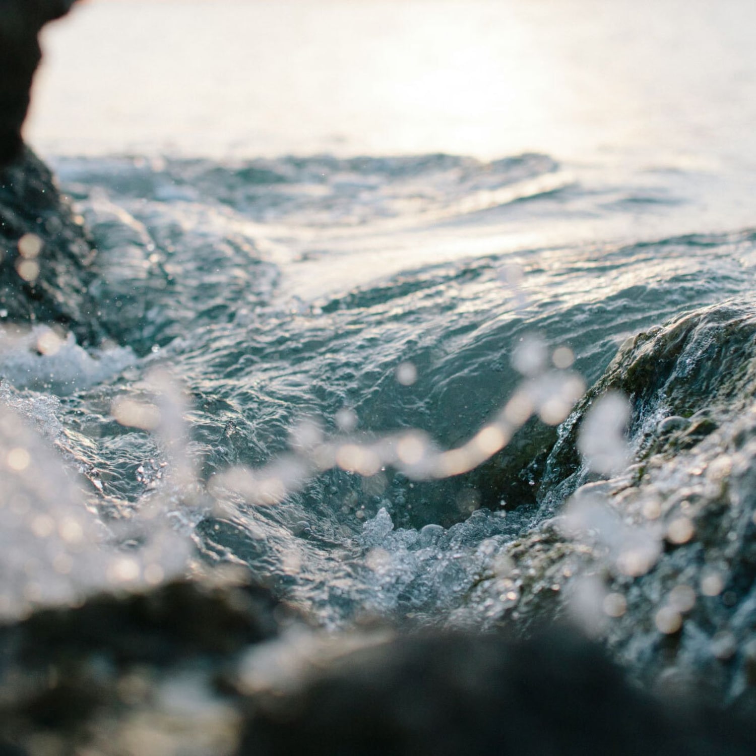 L'immagine mostra l'acqua che si infrange sulle rocce, creando spruzzi e movimento, evocando una sensazione di freschezza e vitalità.