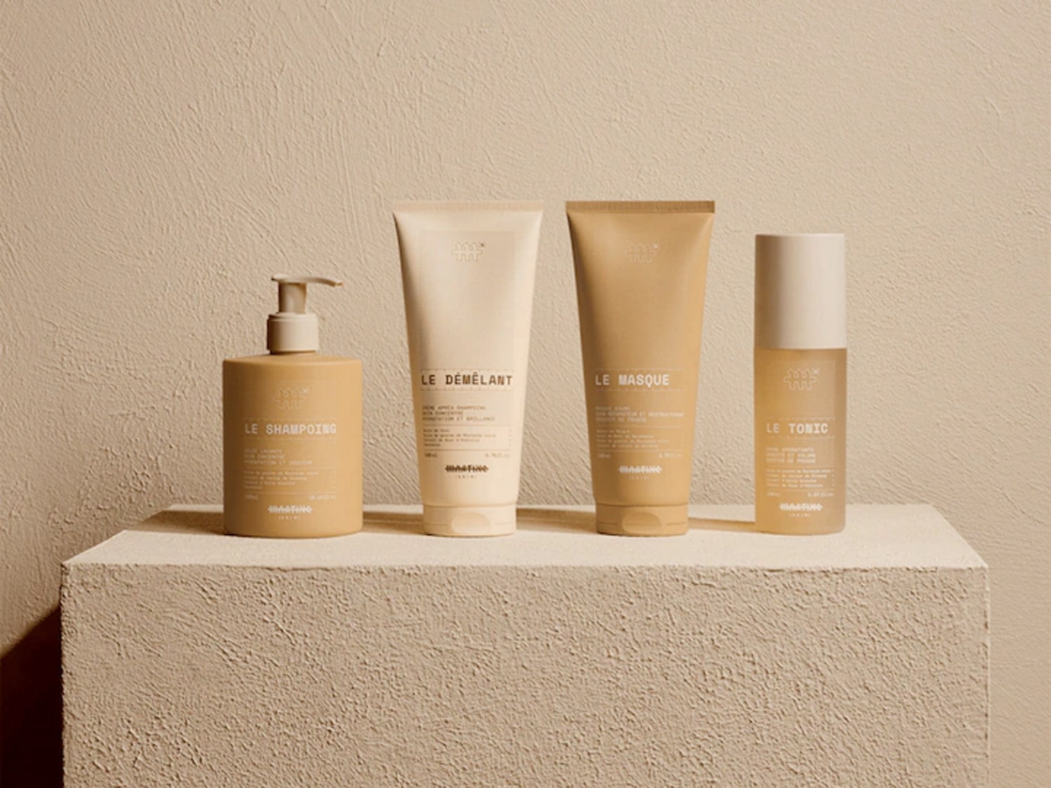 Découvrez une gamme de produits capillaires dans des tons neutres : shampoing en flacon pompe, démêlant en tube, masque et tonique en flacon cylindrique.