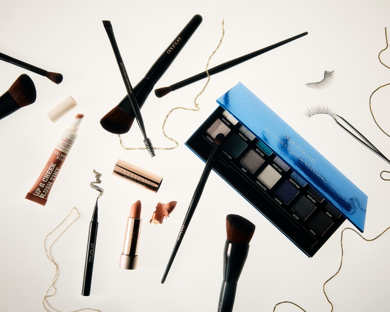 Entdecke eine Auswahl an Make-up-Produkten, darunter die Interstellar Smokey Palette von Douglas, Lippen- und Wangen-Rouge von Kylie Jenner und einen Lippenstift von Anastasia Beverly Hills, um deinen Look zu vervollständigen.