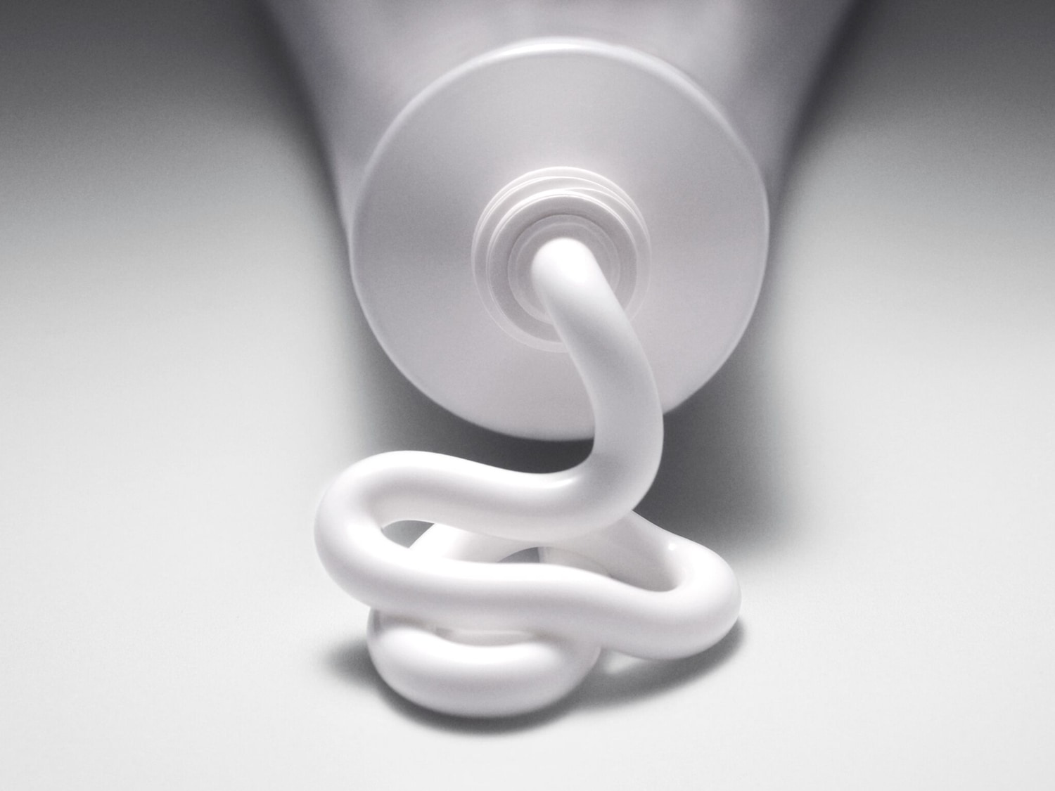 Nahaufnahme einer Tube mit weißer Creme, die in einer gewundenen Form herausgedrückt wird, ideal für Hautpflege oder Schönheitsprodukte.