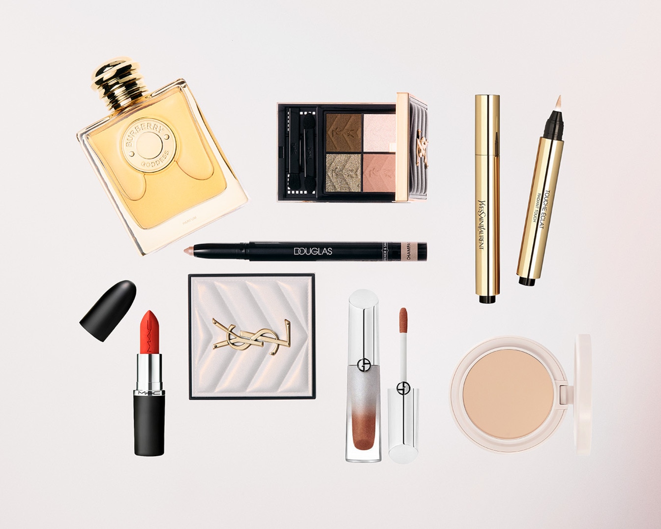 Nuotraukoje matomi įvairūs kosmetikos gaminiai, įskaitant „Burberry“ kvepalus aukso spalvos buteliuke, „MAC“ raudoną lūpų dažą su juodu dangteliu ir „Yves Saint Laurent“ makiažo paletę.