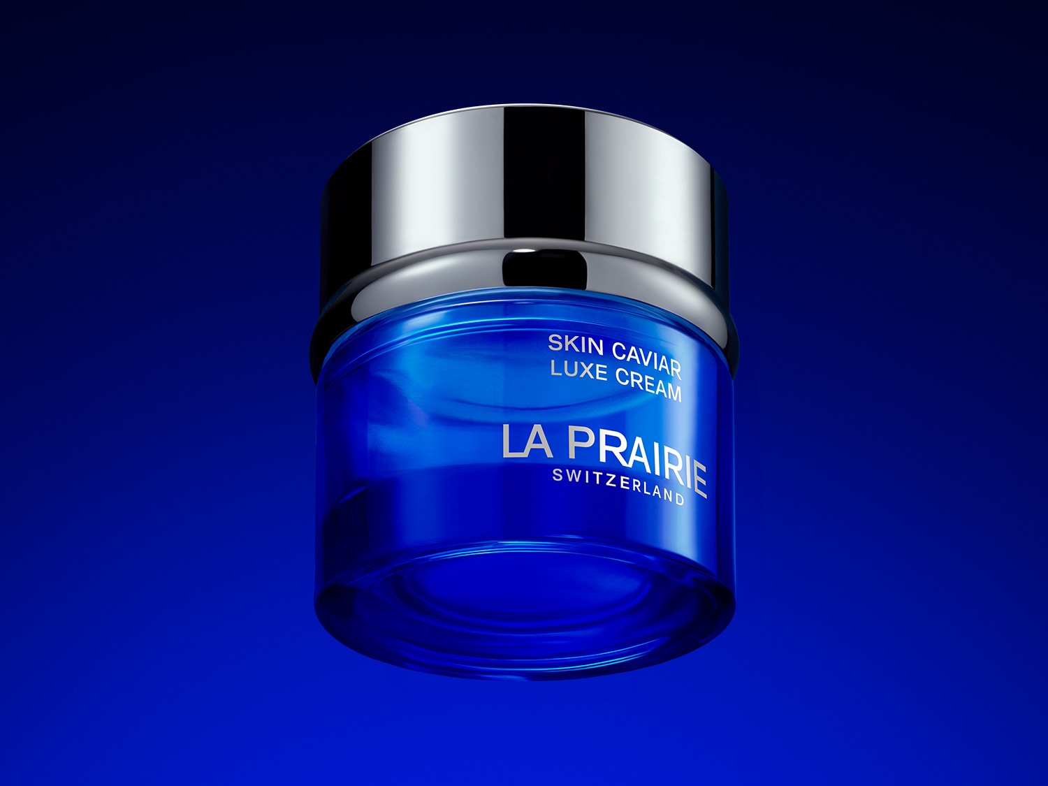 Nahaufnahme eines Tiegels La Prairie Skin Caviar Luxe Cream mit silbernem Deckel vor blauem Hintergrund.