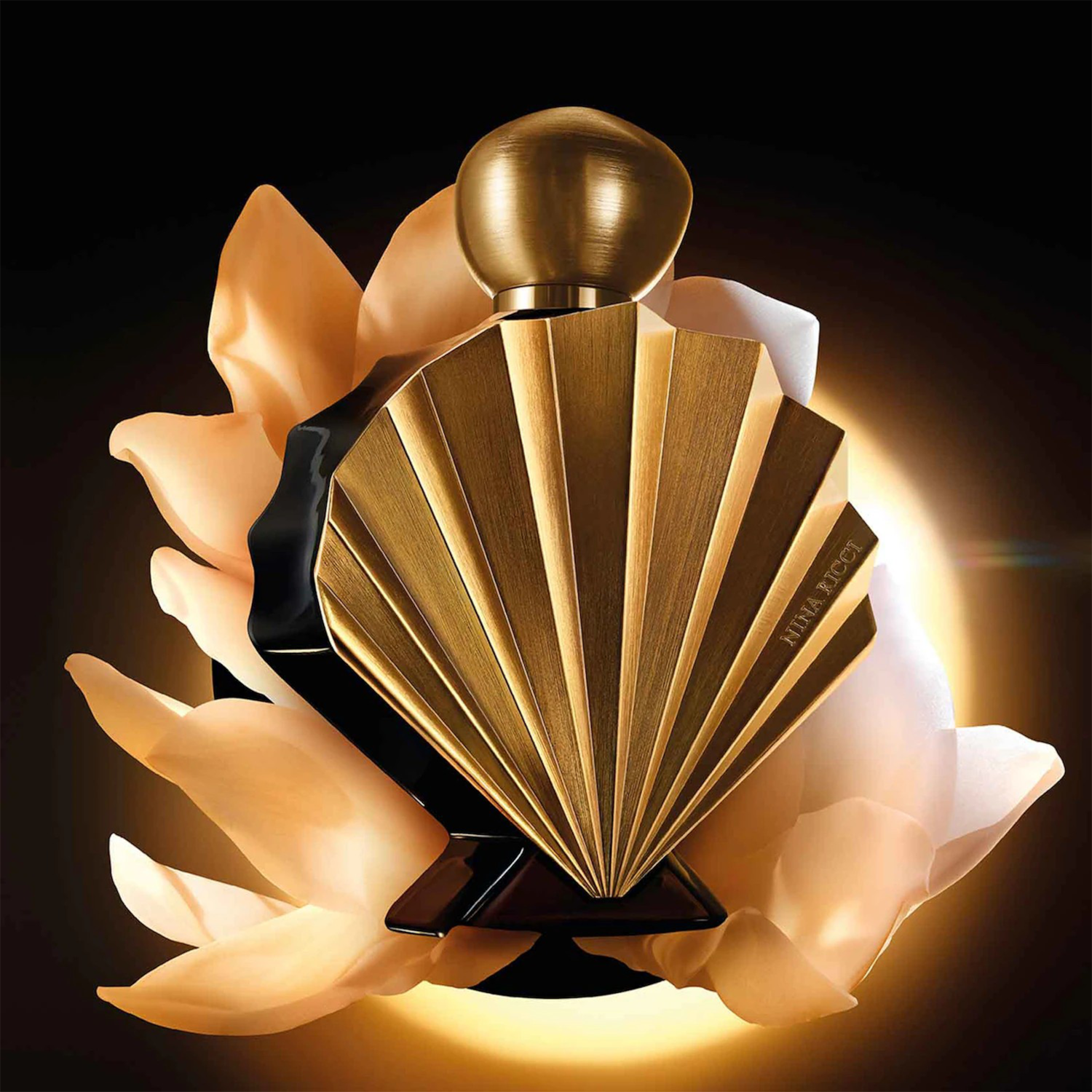 Découvrez le parfum Nina Ricci dans un flacon doré en forme d'éventail, élégamment présenté sur un lit de pétales délicats.