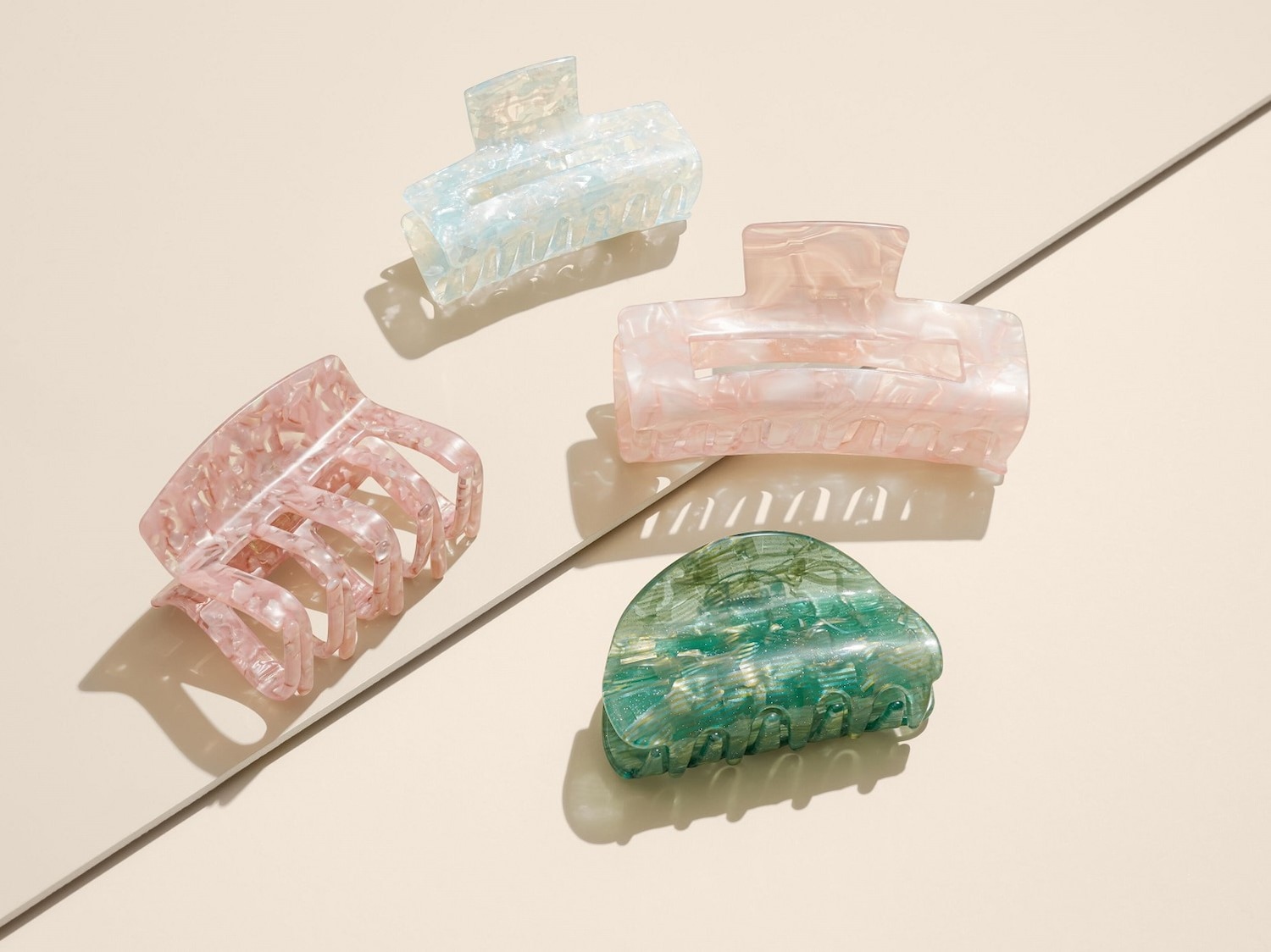 Verschiedene Haarspangen in Pastellfarben, darunter Blau, Rosa und Grün, mit einem schimmernden, marmorierten Effekt.