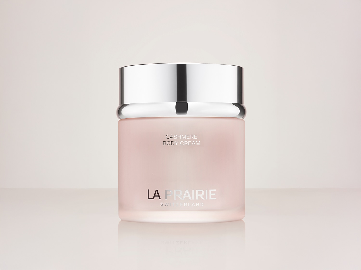 Nahaufnahme einer La Prairie Cashmere Body Cream in einem zarten rosa Behälter mit silbernem Deckel, die luxuriöse und feuchtigkeitsspendende Pflege verspricht.