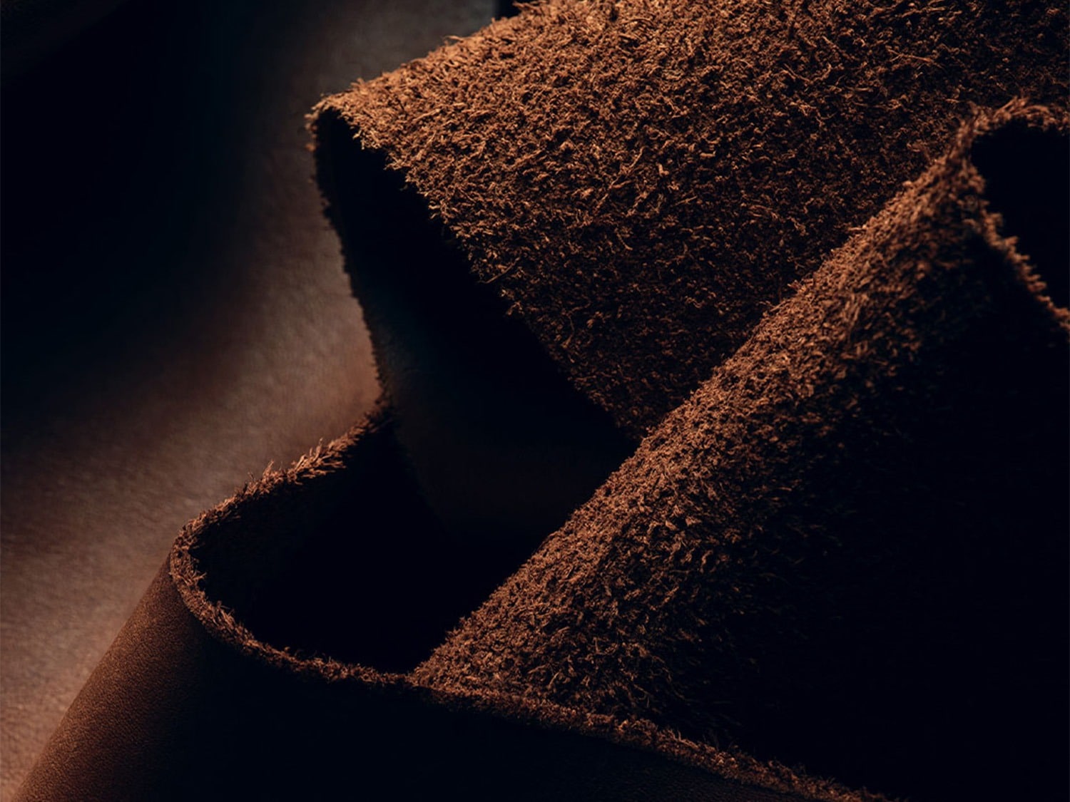 Een close-up van een stuk bruin leer, met een ruwe textuur aan de ene kant en een gladde afwerking aan de andere kant.