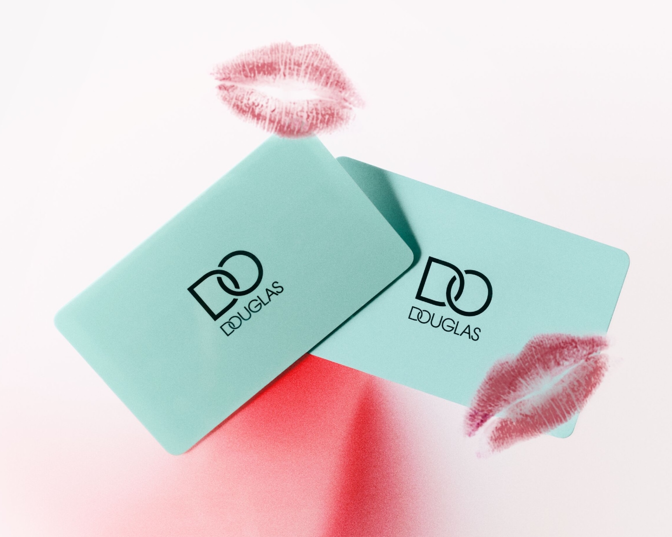 Dwa turkusowe bony upominkowe Douglas z odciskiem ust na białym tle.