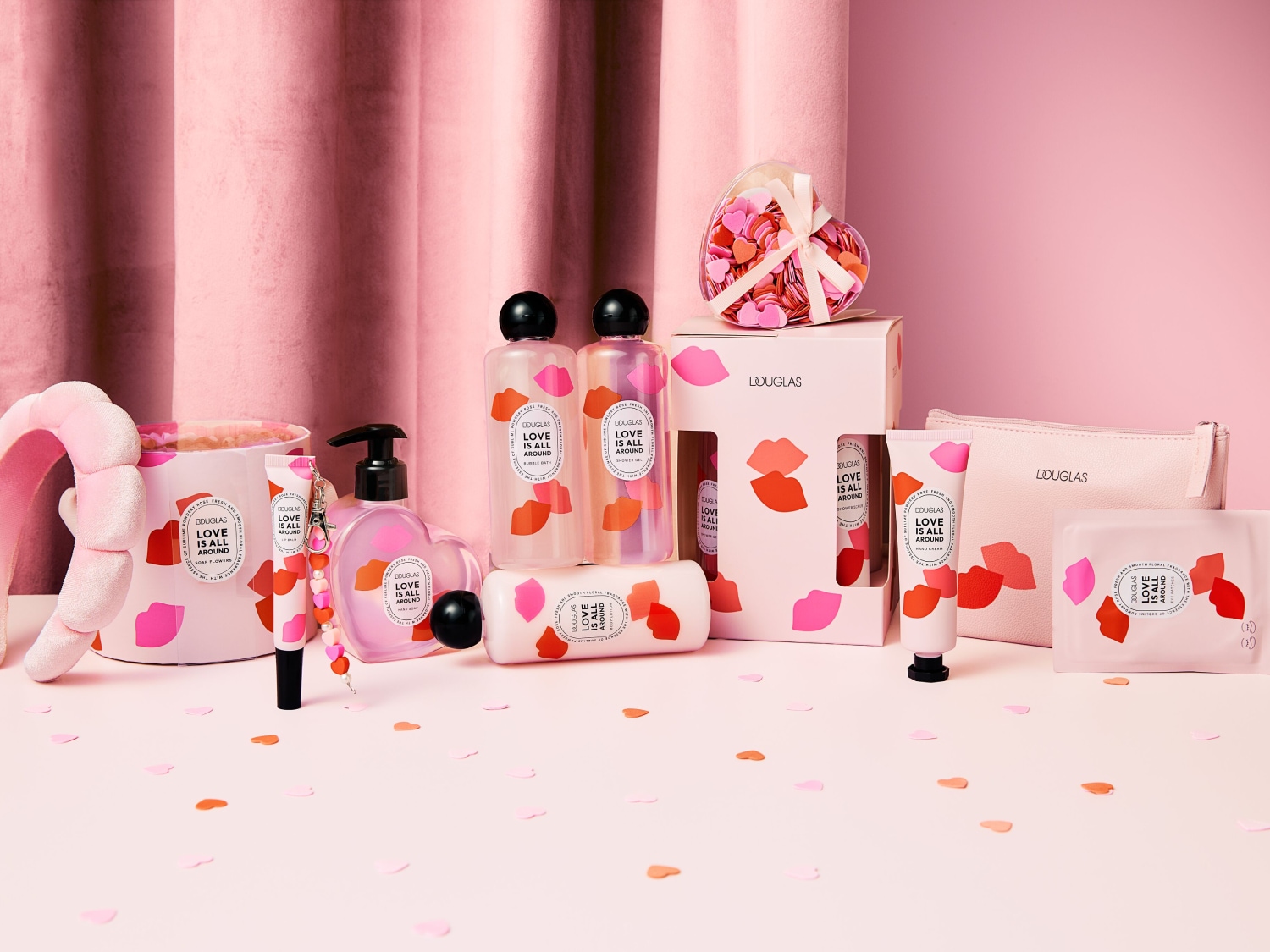 Różowa kolekcja kosmetyków Douglas „Love is all around” z motywem ust, obejmująca żel pod prysznic, balsam do ciała, krem do rąk i akcesoria do pielęgnacji.