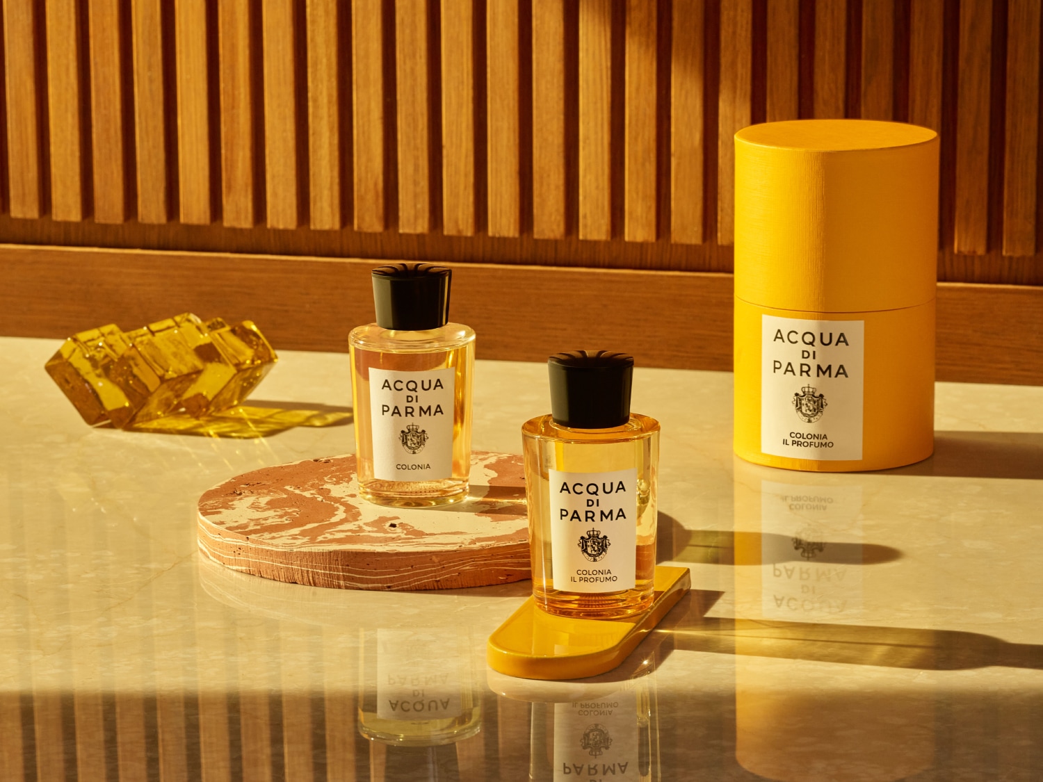 Entdecken Sie Acqua di Parma Colonia, ein Duftklassiker in einer klaren Glasflasche mit schwarzem Verschluss, präsentiert in einer gelben Verpackung.