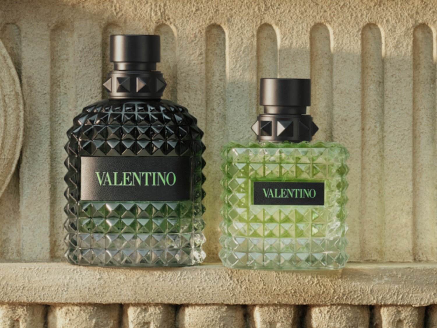 Két Valentino parfümös üveg látható, az egyik sötét, a másik világos zöld, mindkettő jellegzetes, szegecses mintázattal.