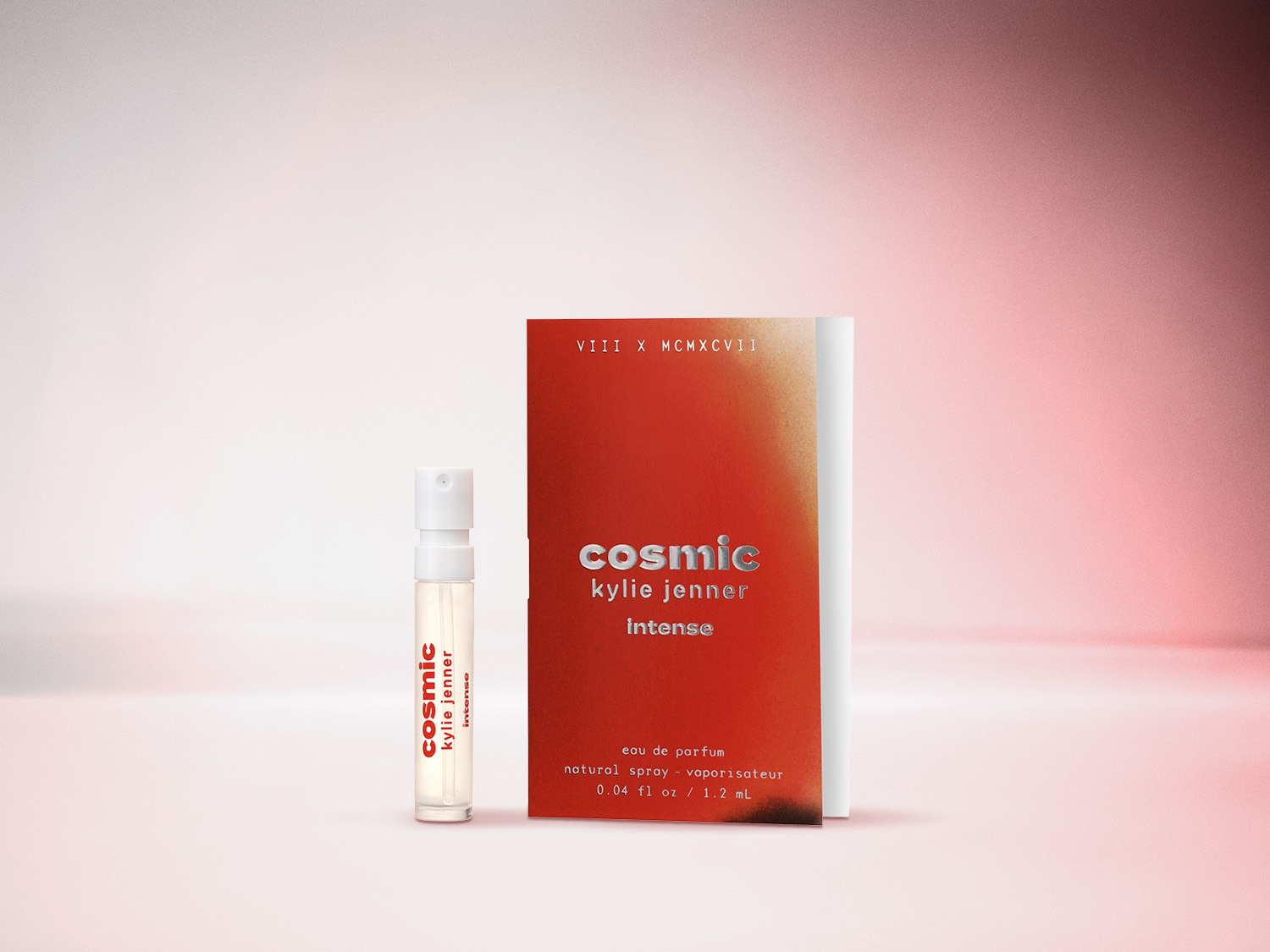 Ein Fläschchen Cosmic Kylie Jenner Intense Eau de Parfum neben der rot-silbernen Verpackung, die den Duftnamen und die Größe von 0,04 fl oz/1,2 ml trägt.