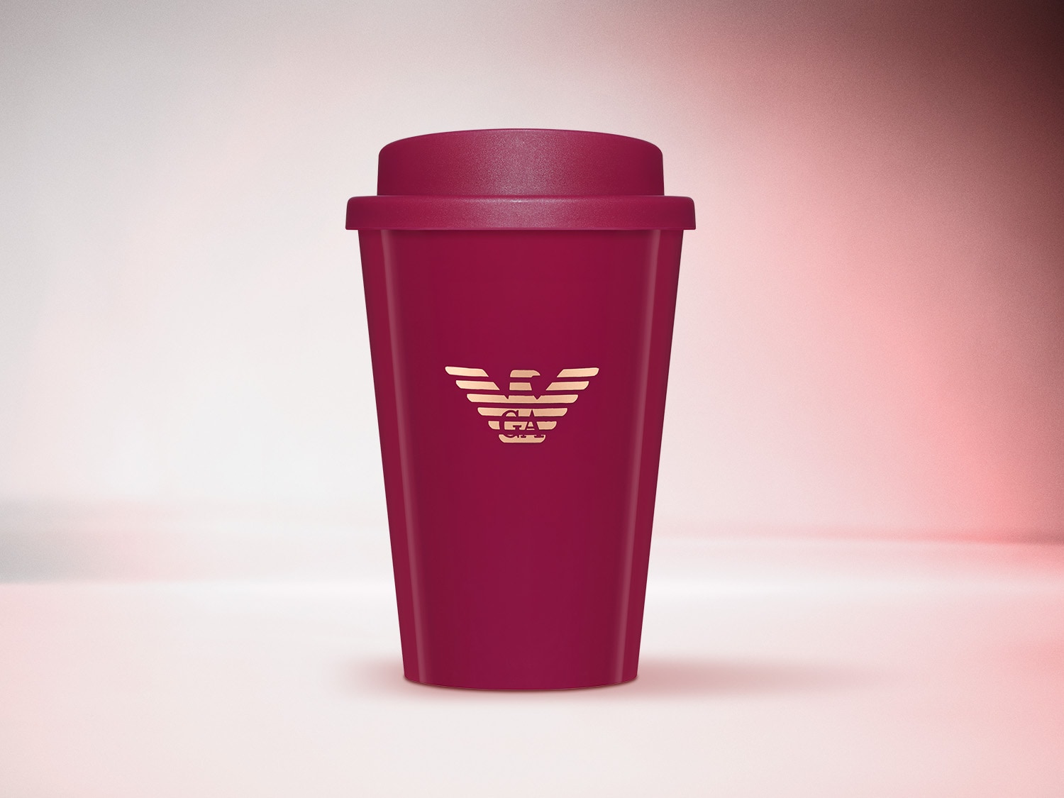 Dunkelroter Reisebecher mit dem goldenen Armani-Logo auf der Vorderseite.