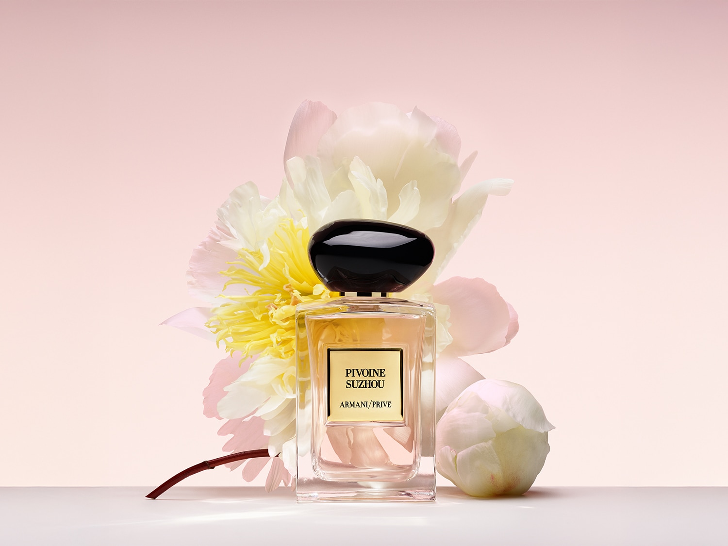 Découvrez Pivoine Suzhou d'Armani Privé, un parfum floral délicat dans un flacon en verre transparent avec un bouchon noir brillant, orné d'une pivoine blanche et jaune.