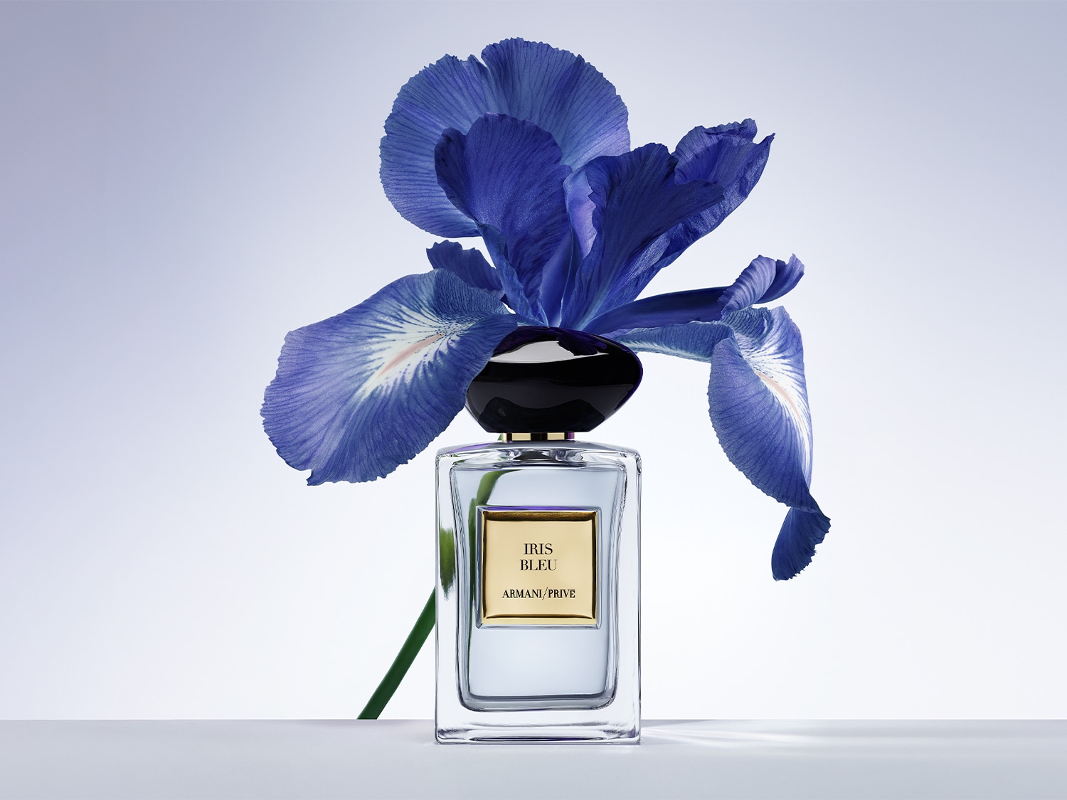 Découvrez Iris Bleu d'Armani Privé, un parfum élégant présenté dans un flacon transparent orné d'une fleur d'iris bleue.