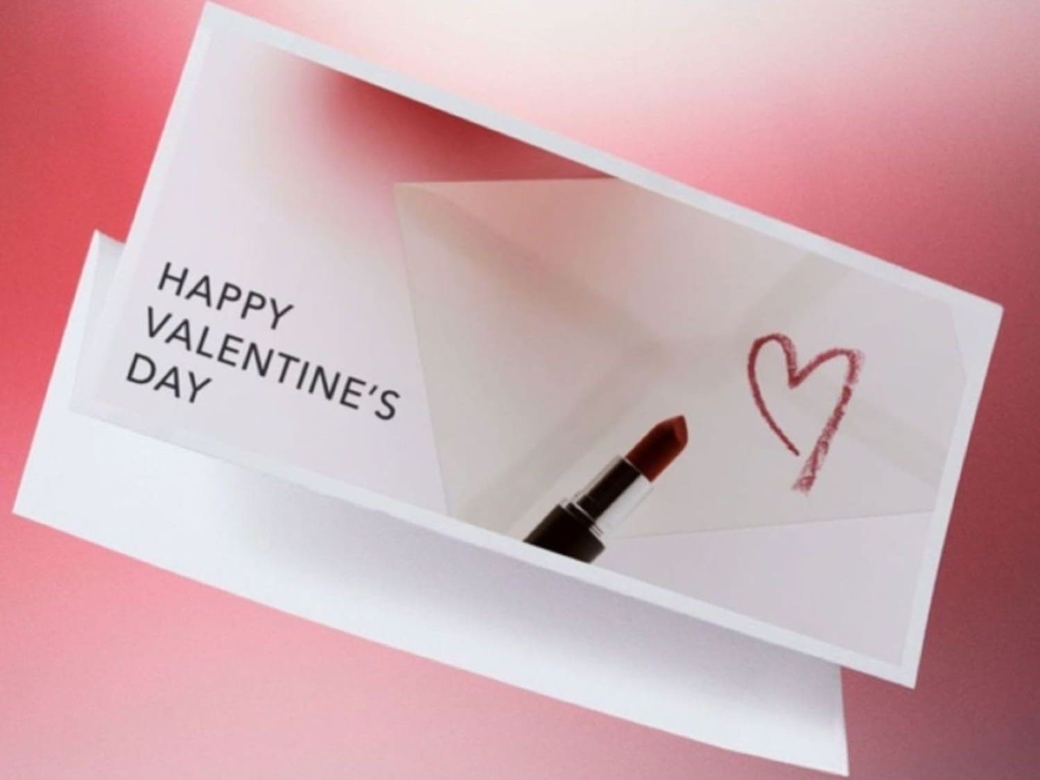 Festeggia San Valentino con un tocco di colore: un rossetto rosso disegna un cuore su un biglietto d'auguri.