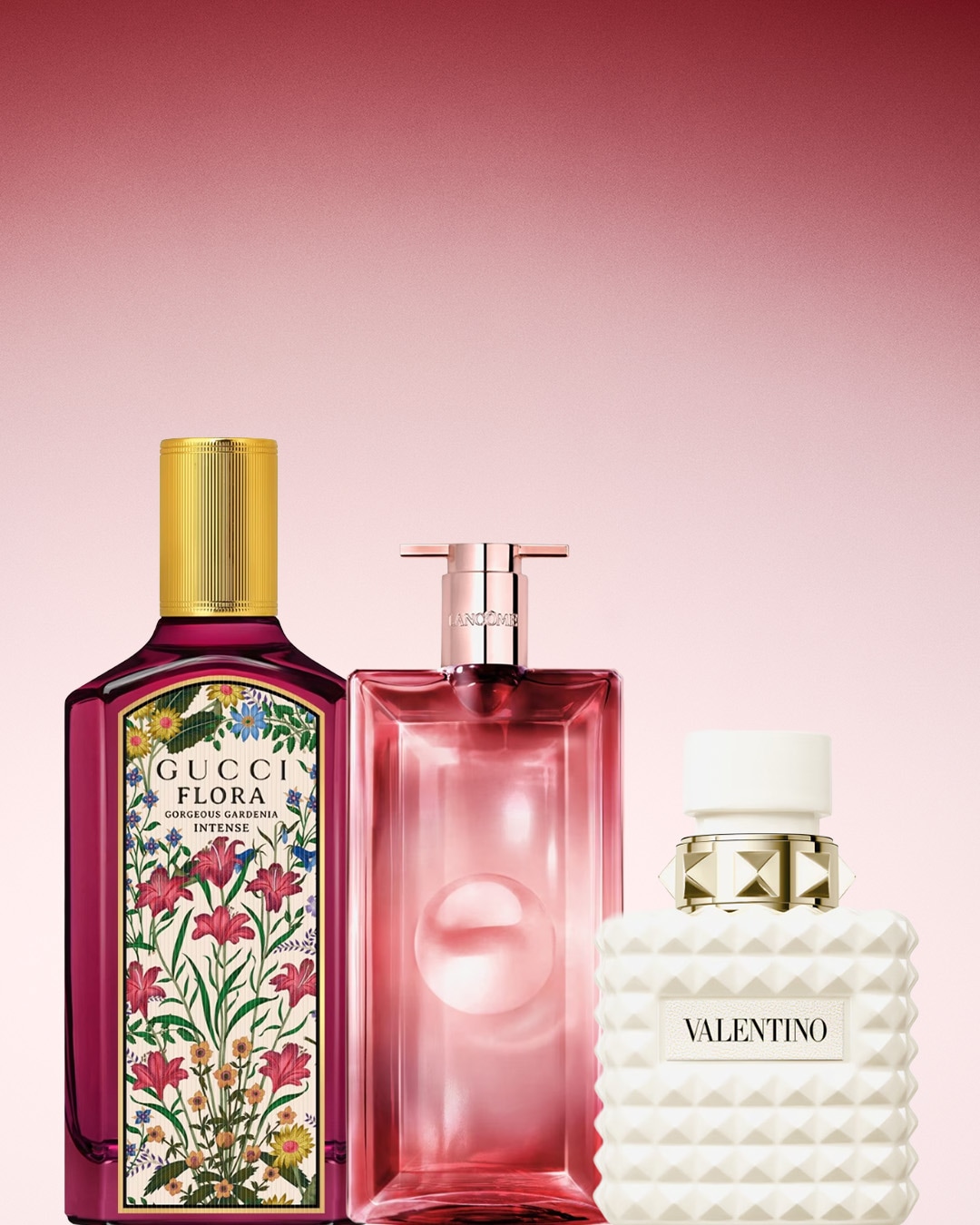 Tre flaconi di profumo di Gucci Flora Gorgeous Gardenia Intense, Lancome e Valentino su sfondo rosa.