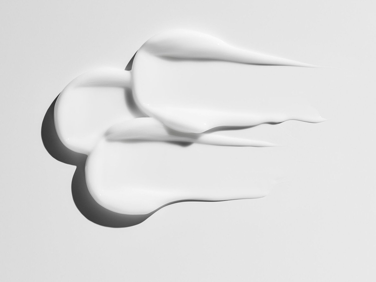 Švelnios tekstūros baltas kremas, tepamas ant šviesaus paviršiaus, sukuria drėkinimo ir švaros pojūtį.