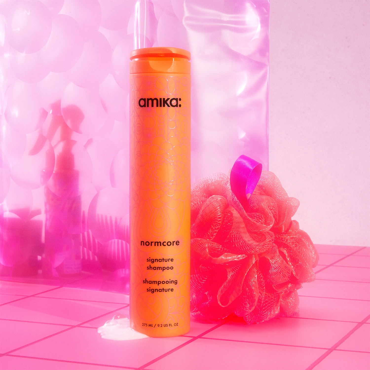 Le shampooing signature Normcore d'Amika dans un flacon orange vif promettant un nettoyage en douceur pour des cheveux éclatants de santé.