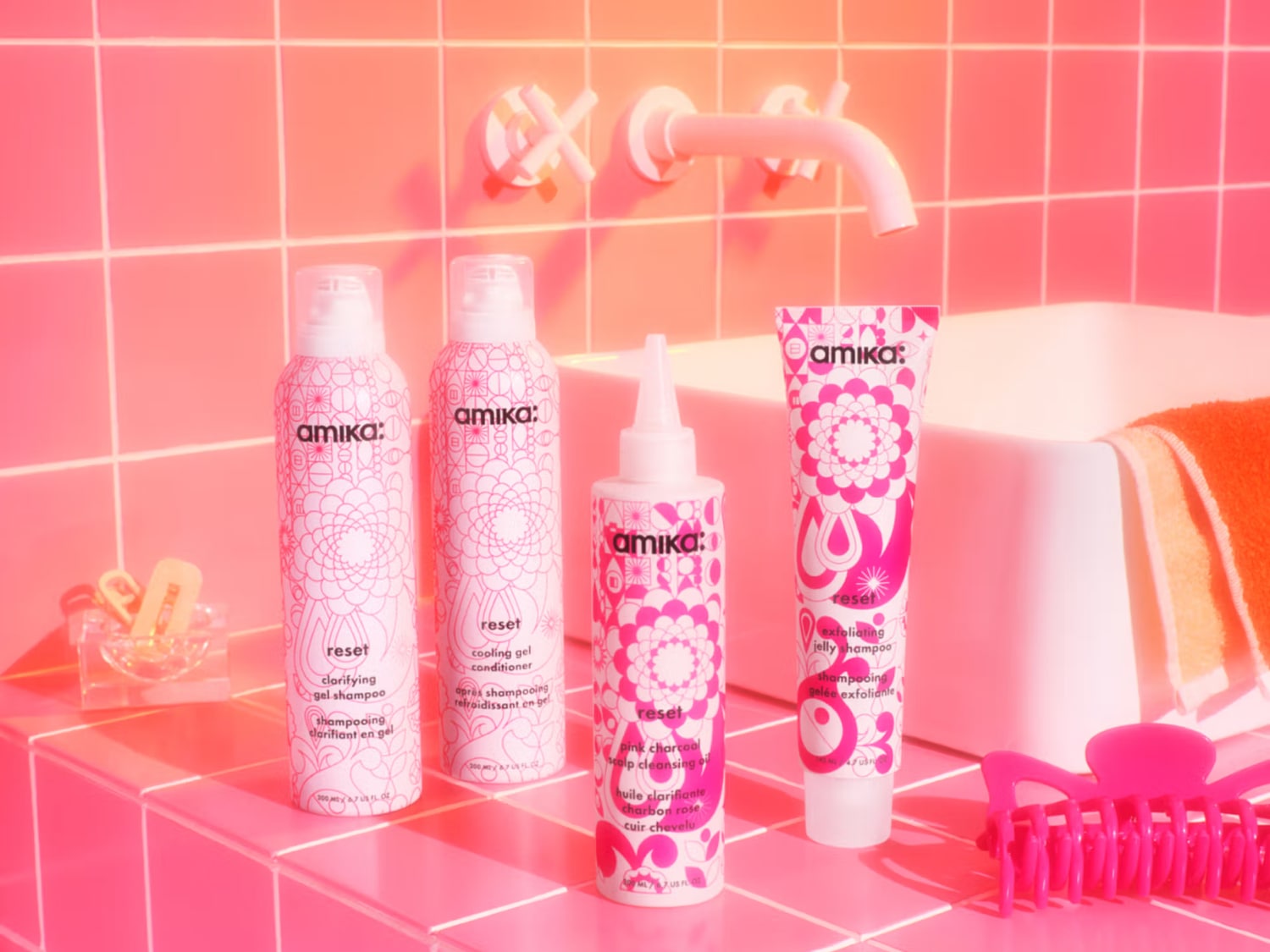 Découvrez la gamme Reset d'Amika : shampooing clarifiant en gel, revitalisant en gel rafraîchissant, huile nettoyante pour le cuir chevelu au charbon rose et shampooing exfoliant en gelée, le tout dans un emballage rose et blanc.