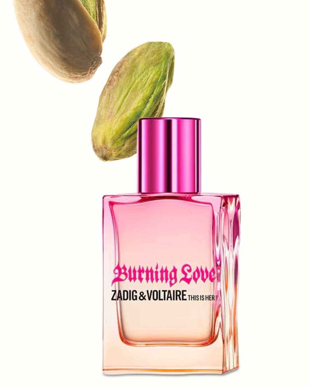 Rosa getönter Glasflakon mit dem Duft „Burning Love“ von Zadig & Voltaire, verziert mit einem pinkfarbenen Deckel und Pistazien im Hintergrund.